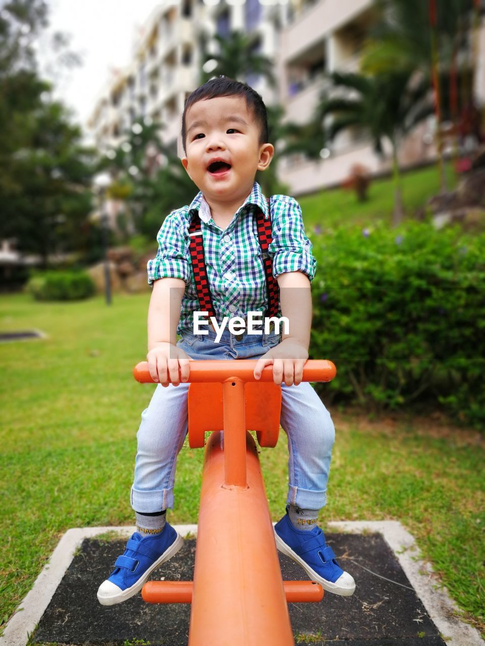 Full length of cute baby boy sitting on seesaw at playground