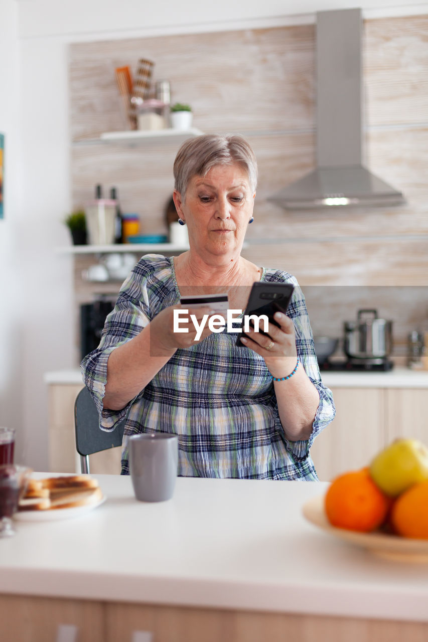 Woman doing online shopping through smart phone at home