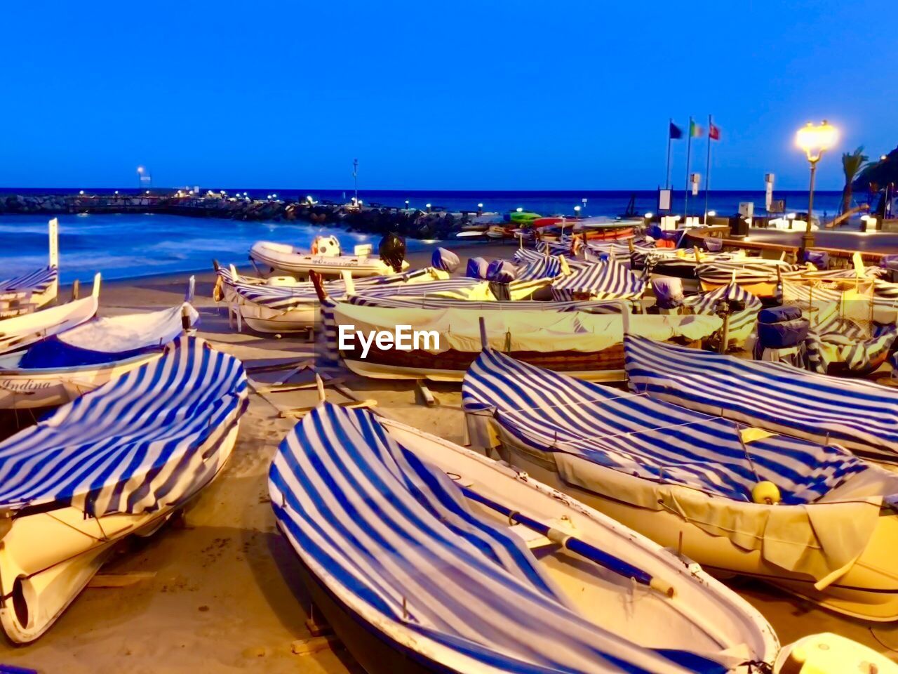 BOATS MOORED ON BEACH AGAINST BLUE SKY