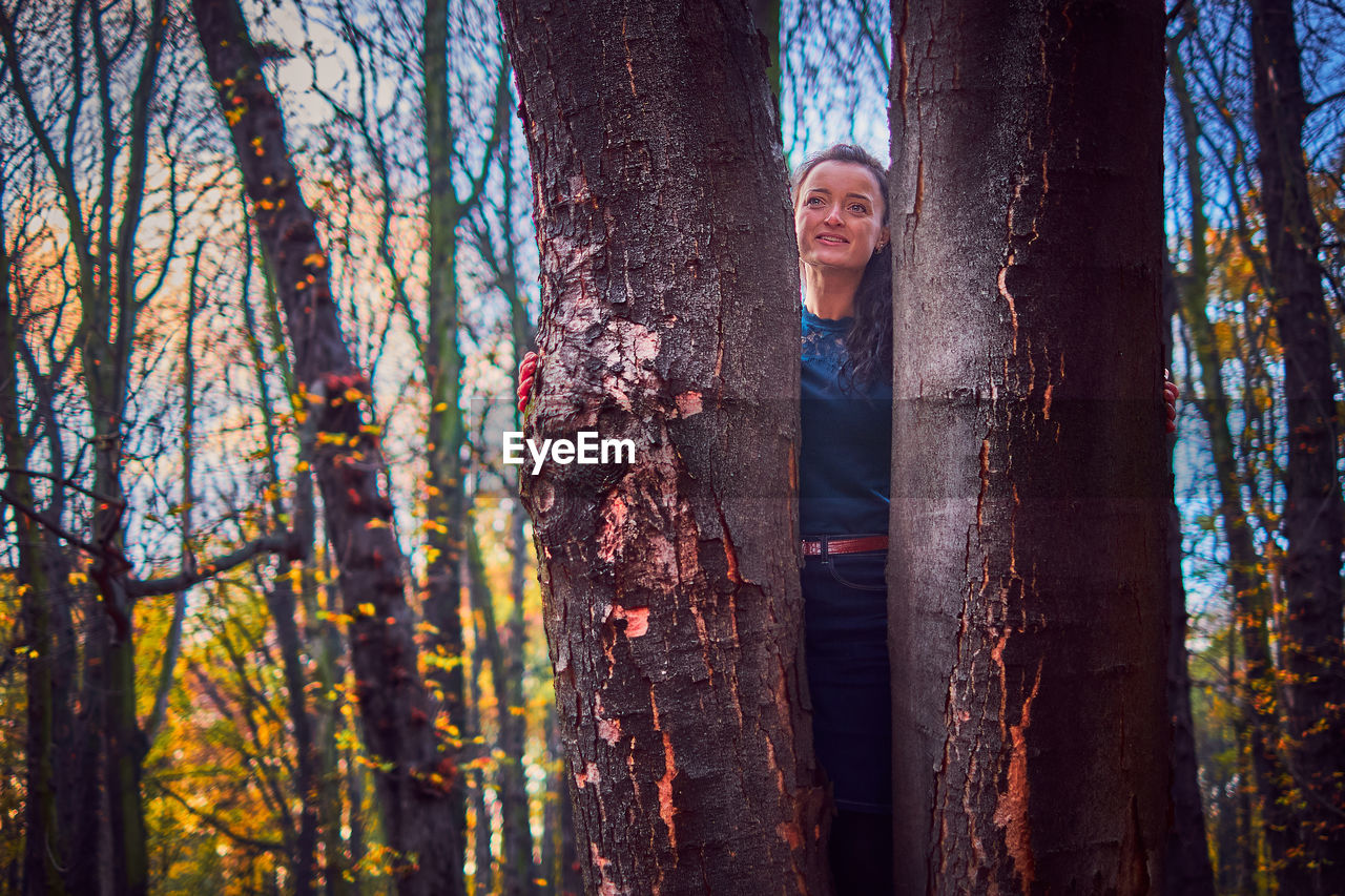 Portrait of smiling woman standing by trees in forest