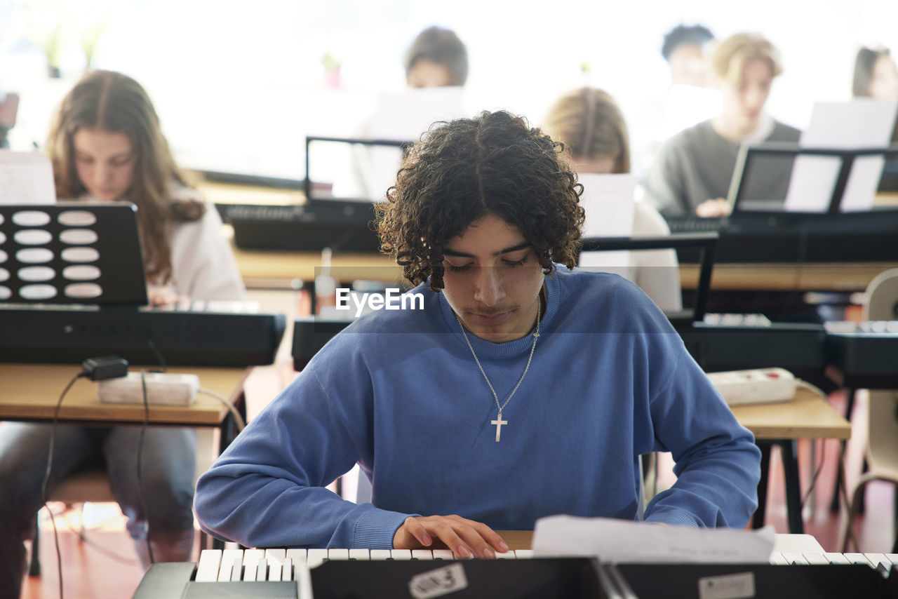 Teenagers attending keyboard lesson