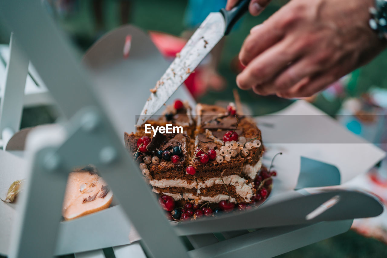 Cropped image of hands cutting cake