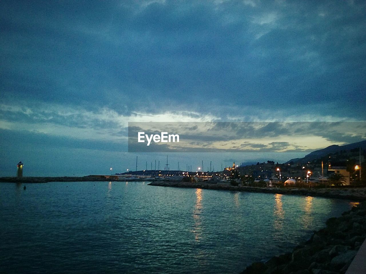 VIEW OF ILLUMINATED CITY AGAINST CLOUDY SKY