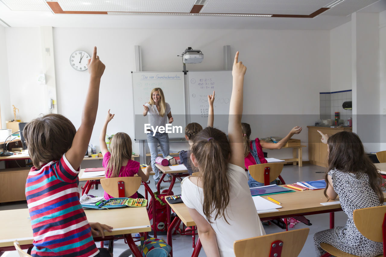 Active pupils raising their hands in class