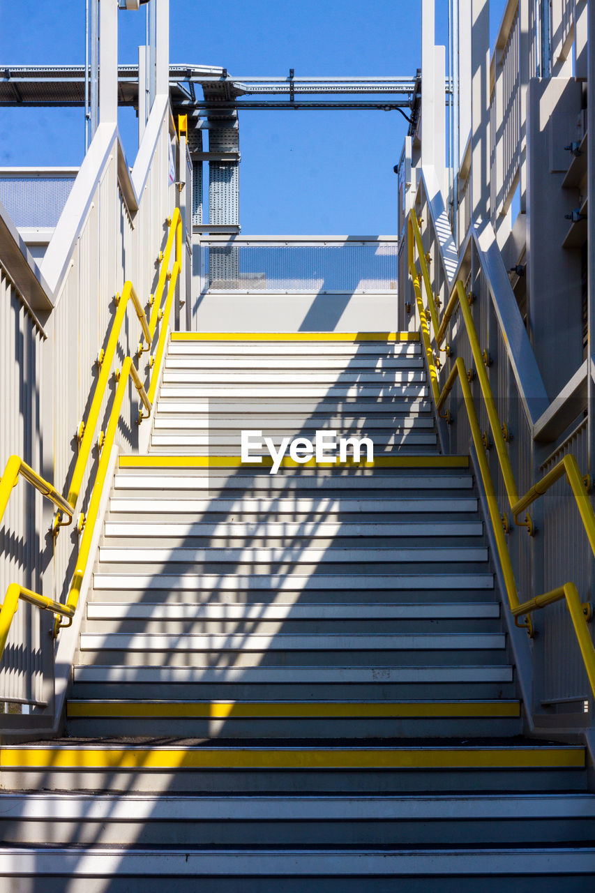 LOW ANGLE VIEW OF STAIRCASE AGAINST BLUE SKY