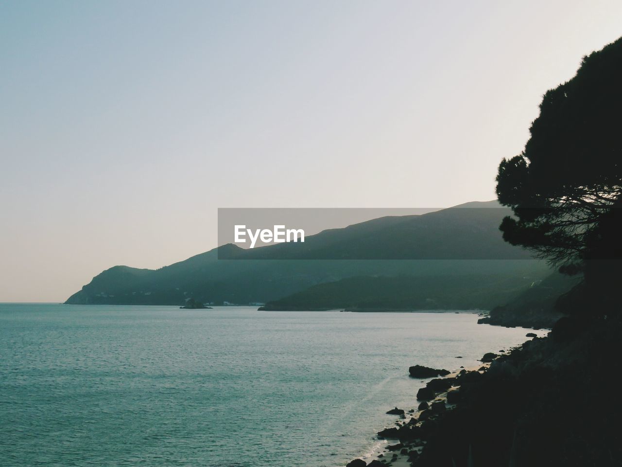 SCENIC VIEW OF SEA AND MOUNTAIN AGAINST CLEAR SKY