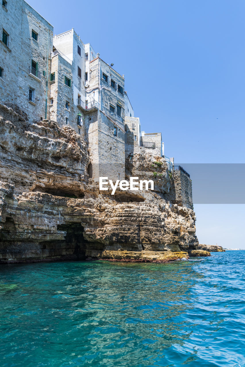 SEA BY ROCKS AGAINST CLEAR BLUE SKY