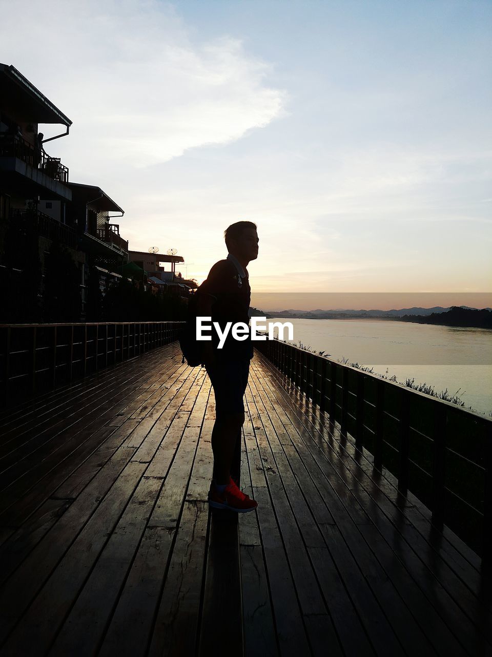 FULL LENGTH OF SILHOUETTE MAN STANDING ON JETTY AGAINST SKY