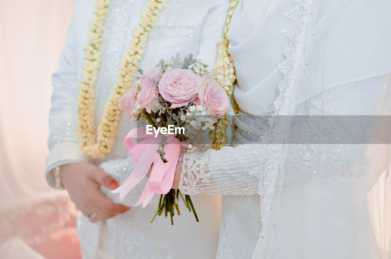 Midsection of wedding bride standing with bouquet of flowers