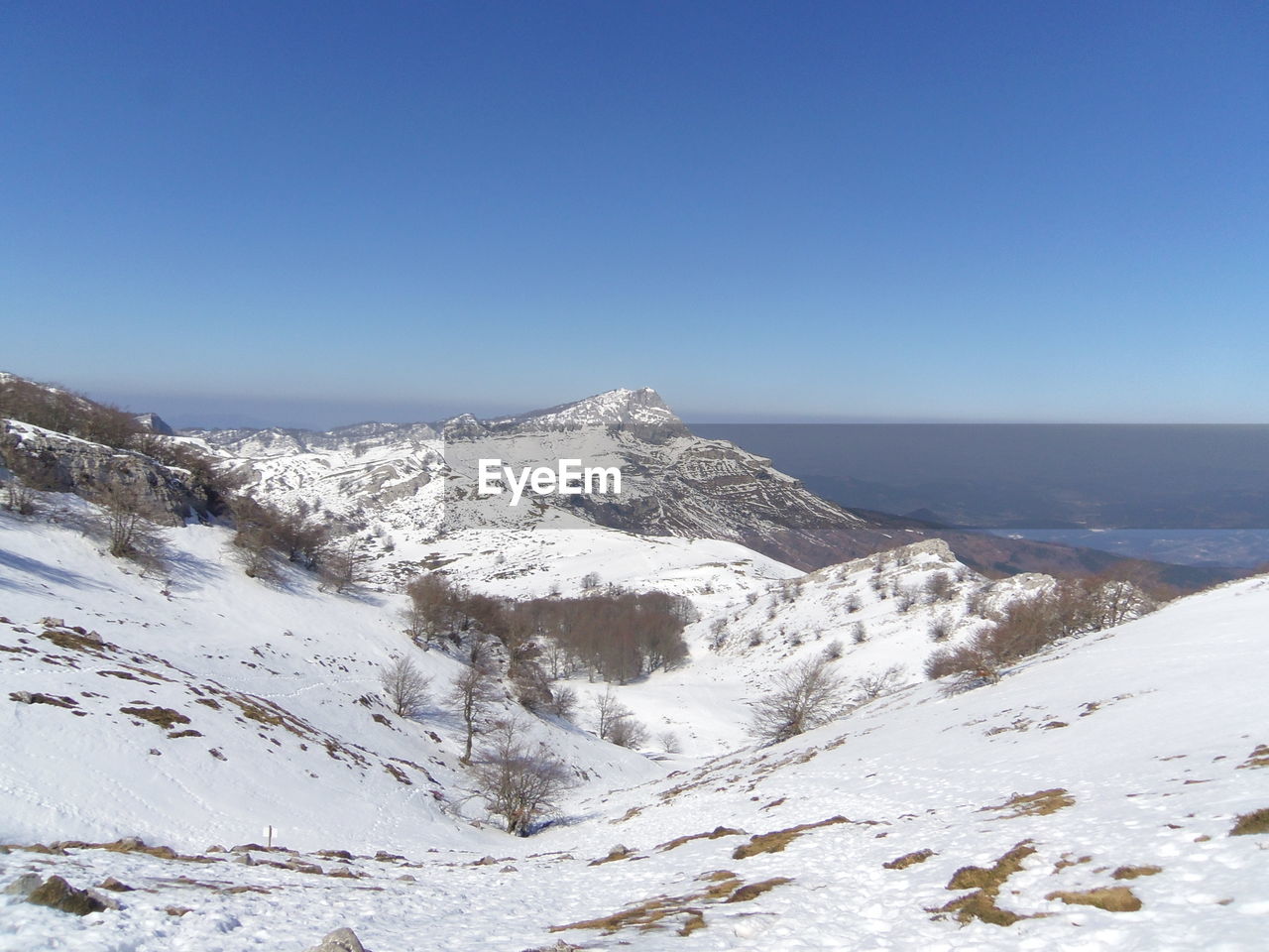 Scenic view of snowcapped mountains against clear blue sky