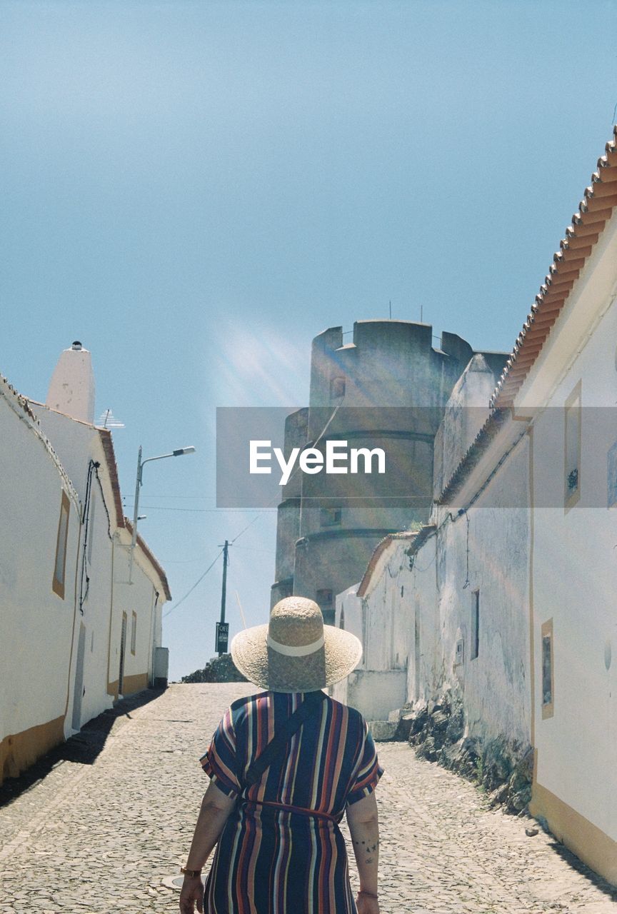 Rear view of woman standing amidst houses on street