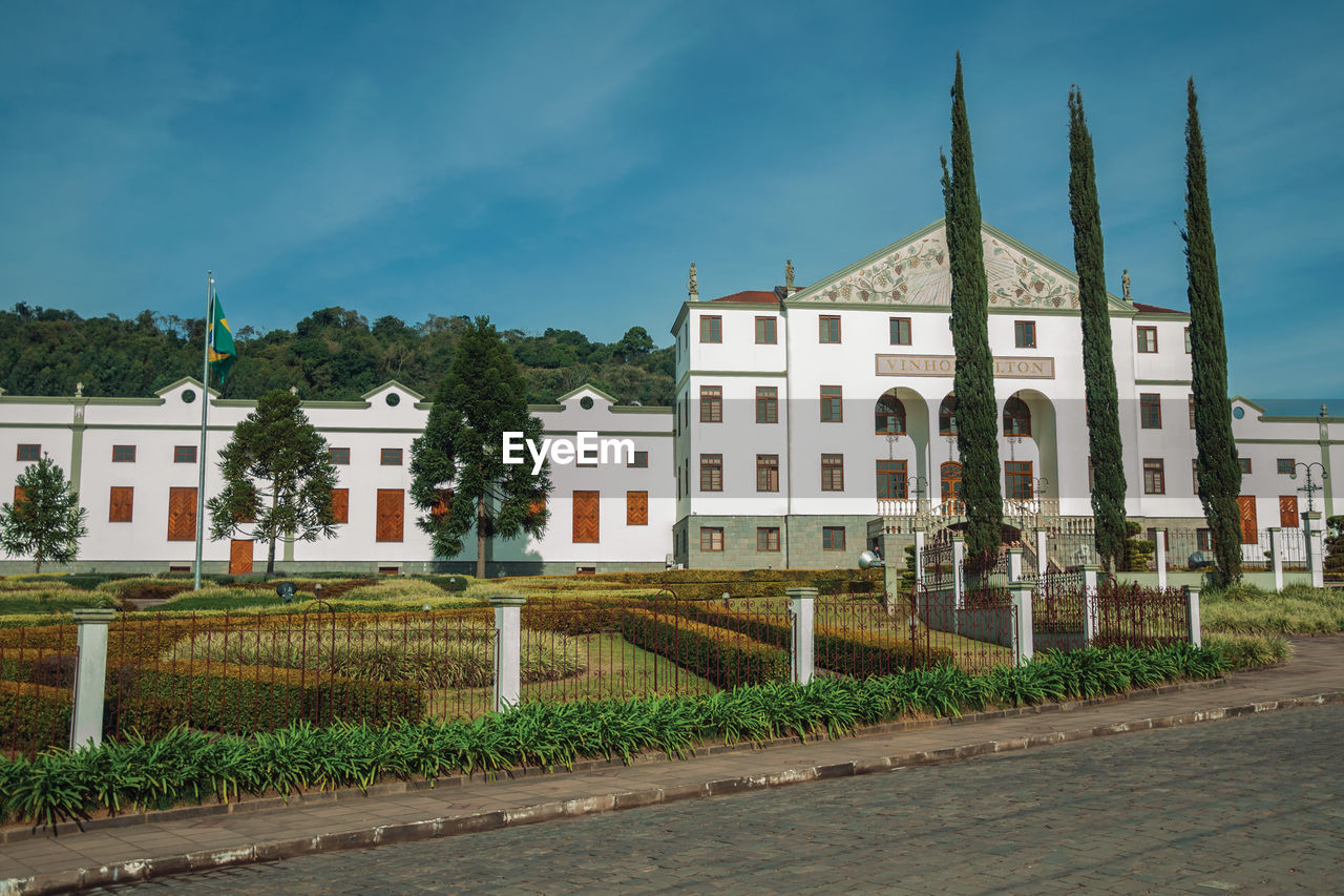 Street with the salton winery headquarter facade behind and gardens near bento goncalves, brasil.