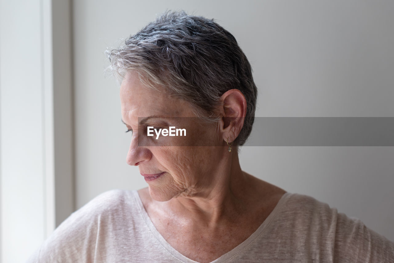 Close-up of mature woman against wall at home