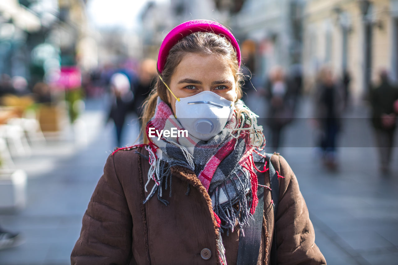 Portrait of woman wearing mask on street in city during winter
