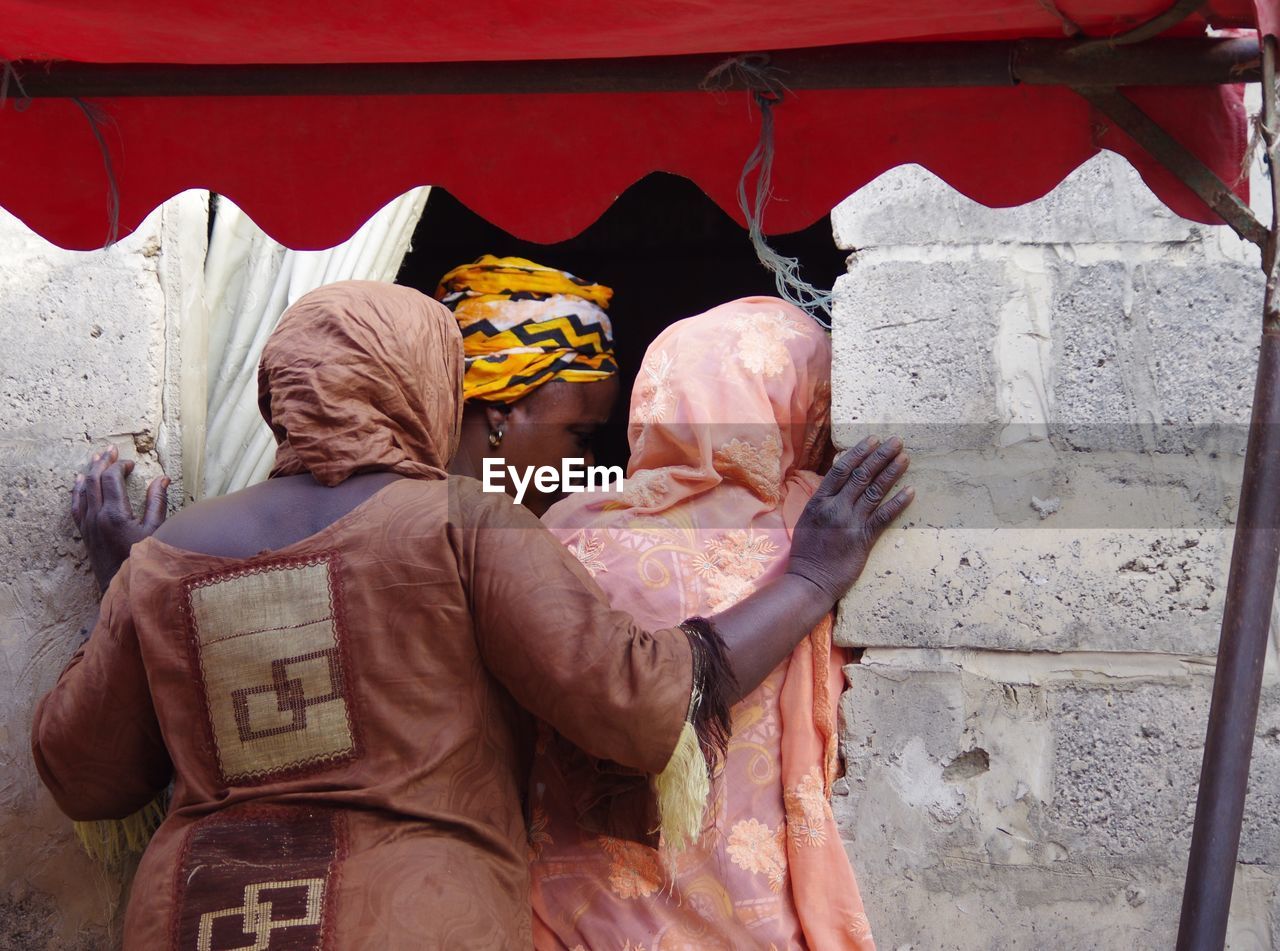 REAR VIEW OF COUPLE HOLDING HANDS ON WALL