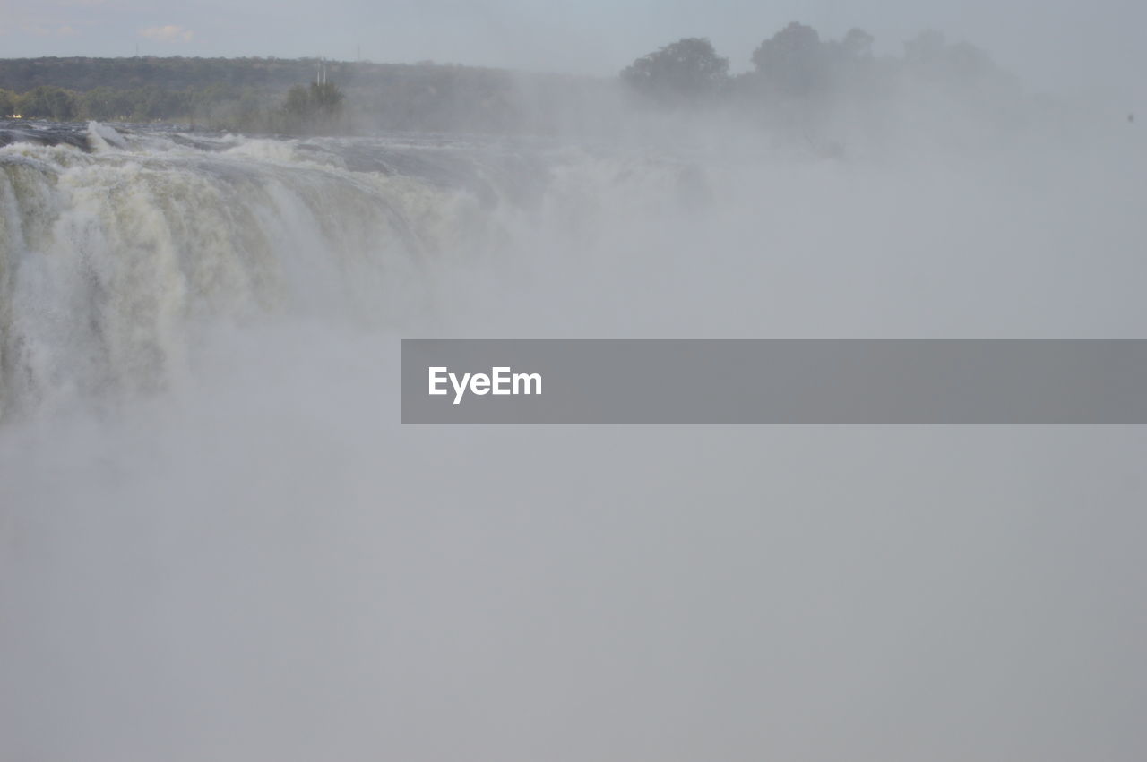 PANORAMIC VIEW OF WATERFALL AGAINST SKY