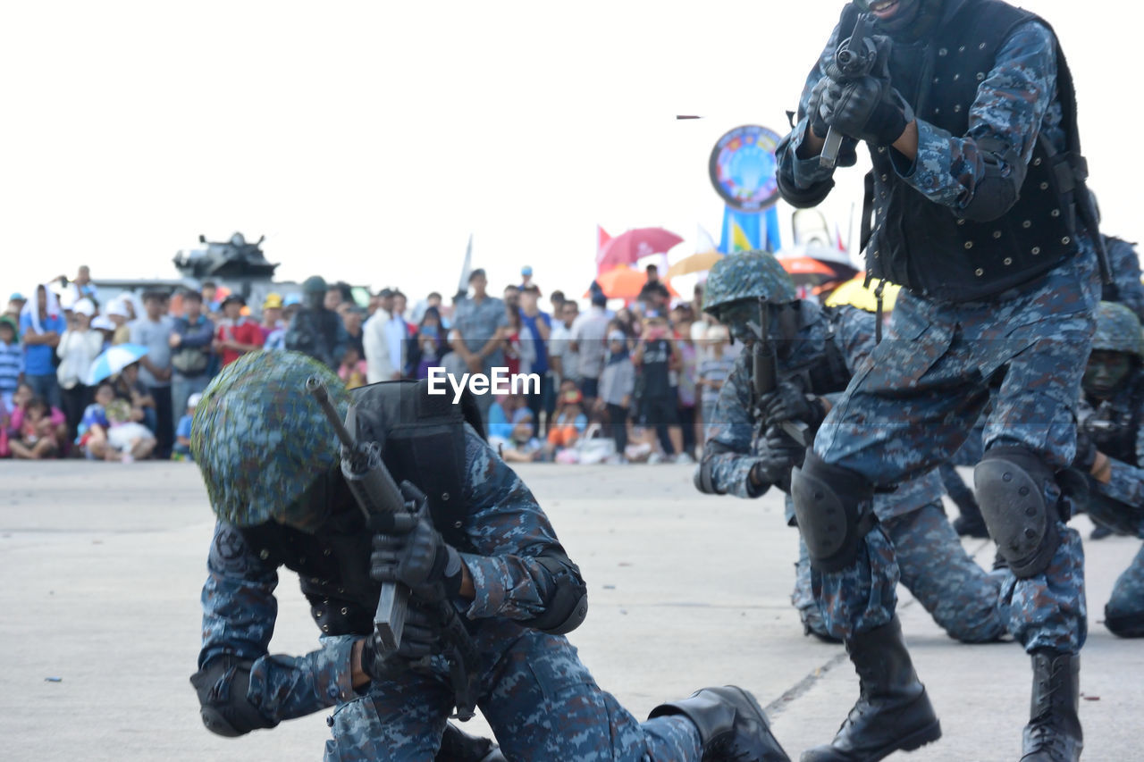 Armed forces performing parade on road with people in background