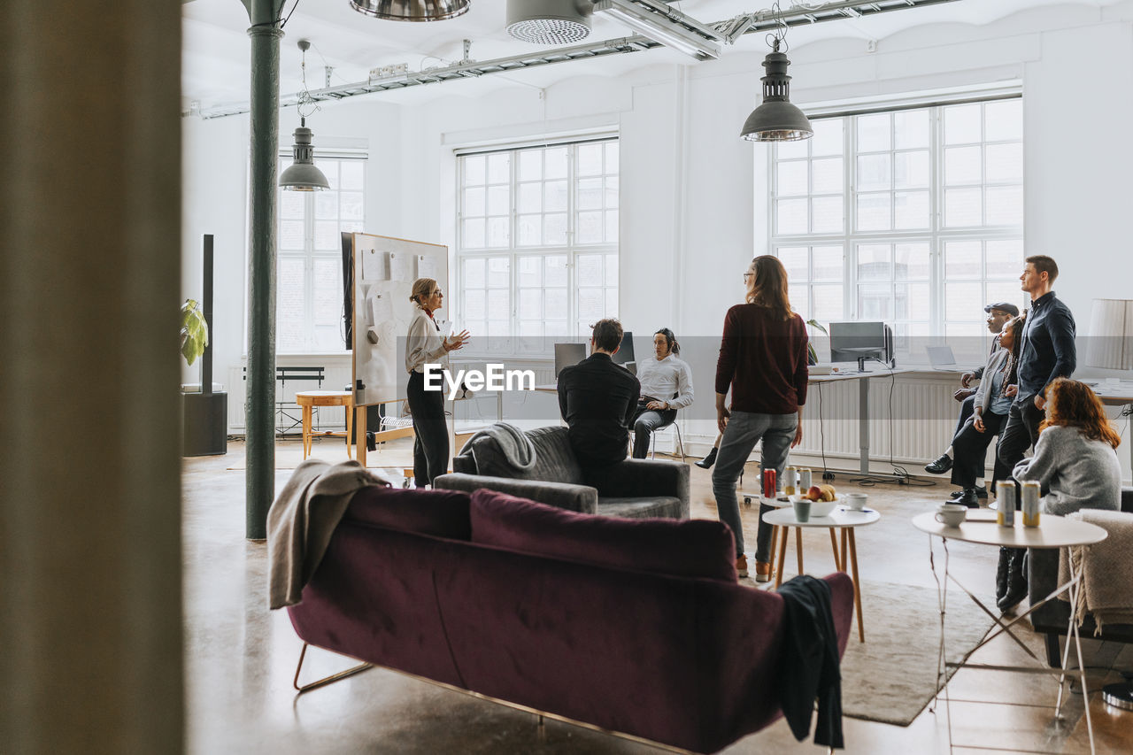 Male and female business people attending meeting with manager at office