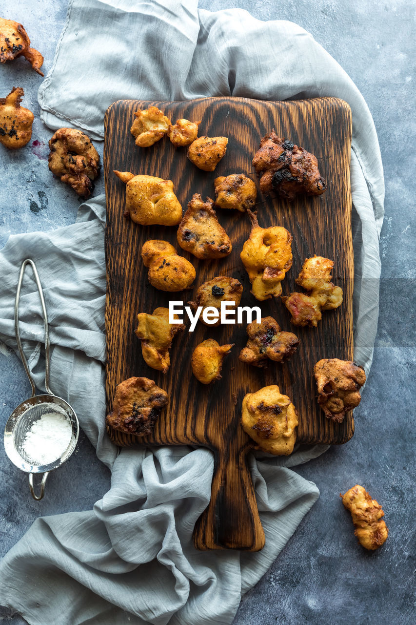 Top down view of homemade deep fried fritters with powdered sugar.
