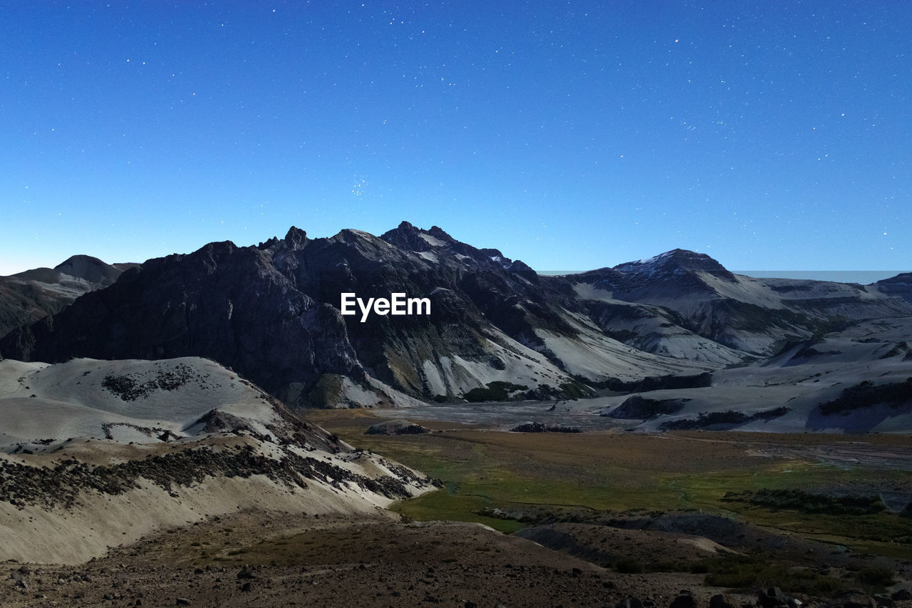 Scenic view of snowcapped mountains against clear blue sky