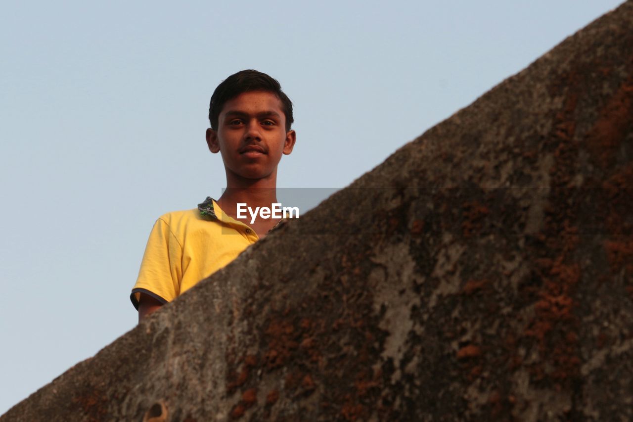 Low angle view man standing by retaining wall against sky