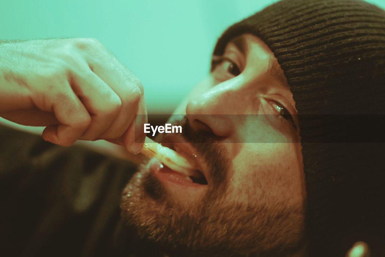 CLOSE-UP PORTRAIT OF MAN HOLDING CIGARETTE IN MOUTH