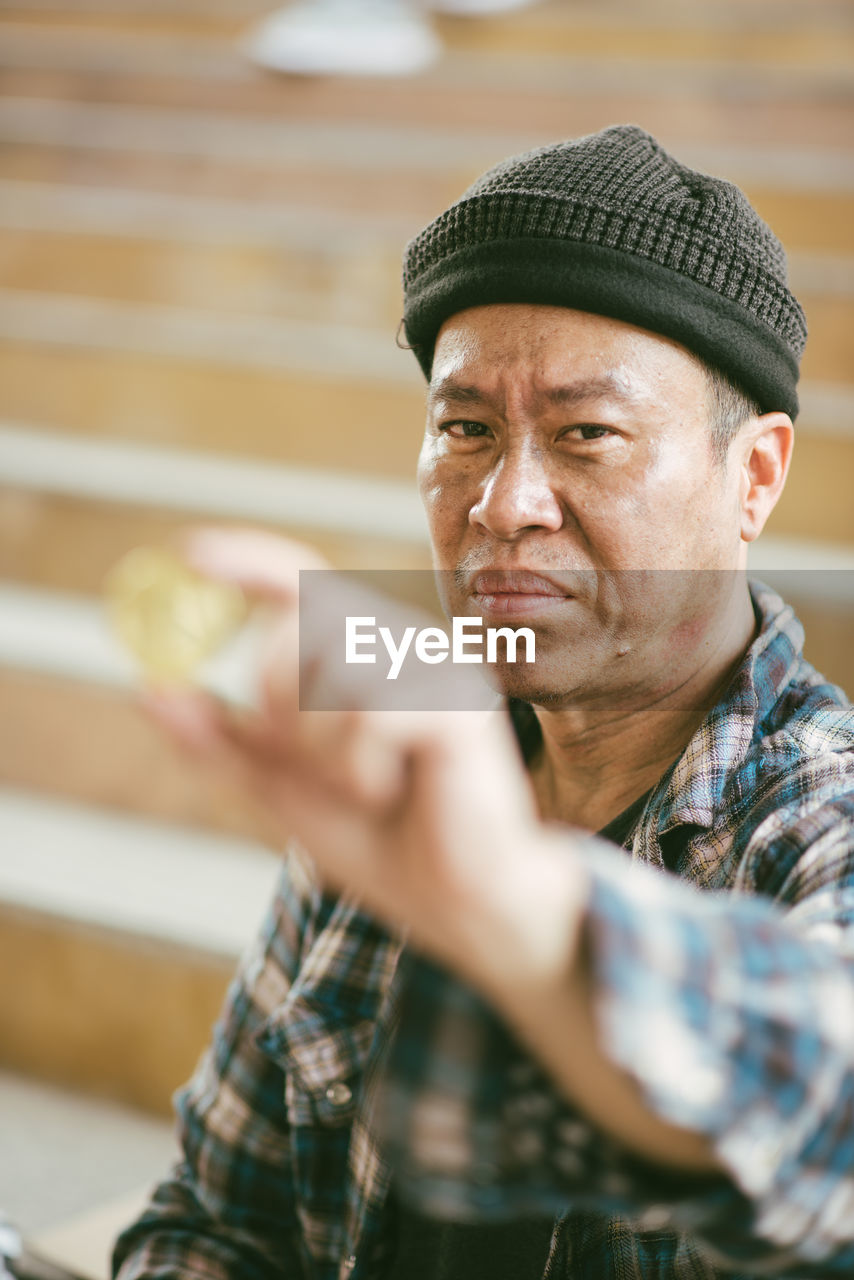 Portrait of beggar holding coin