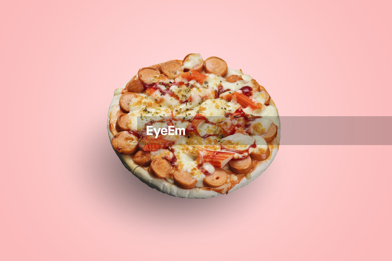 Sausage and crab stick pizza isolated on pastel color background.