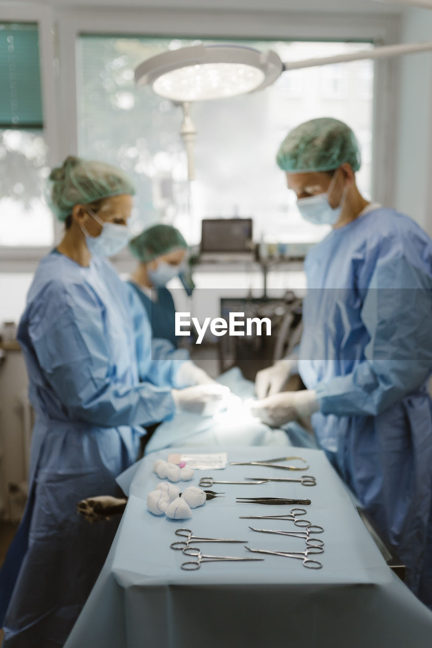 Surgical equipment arranged on table with animal surgeons in background at hospital