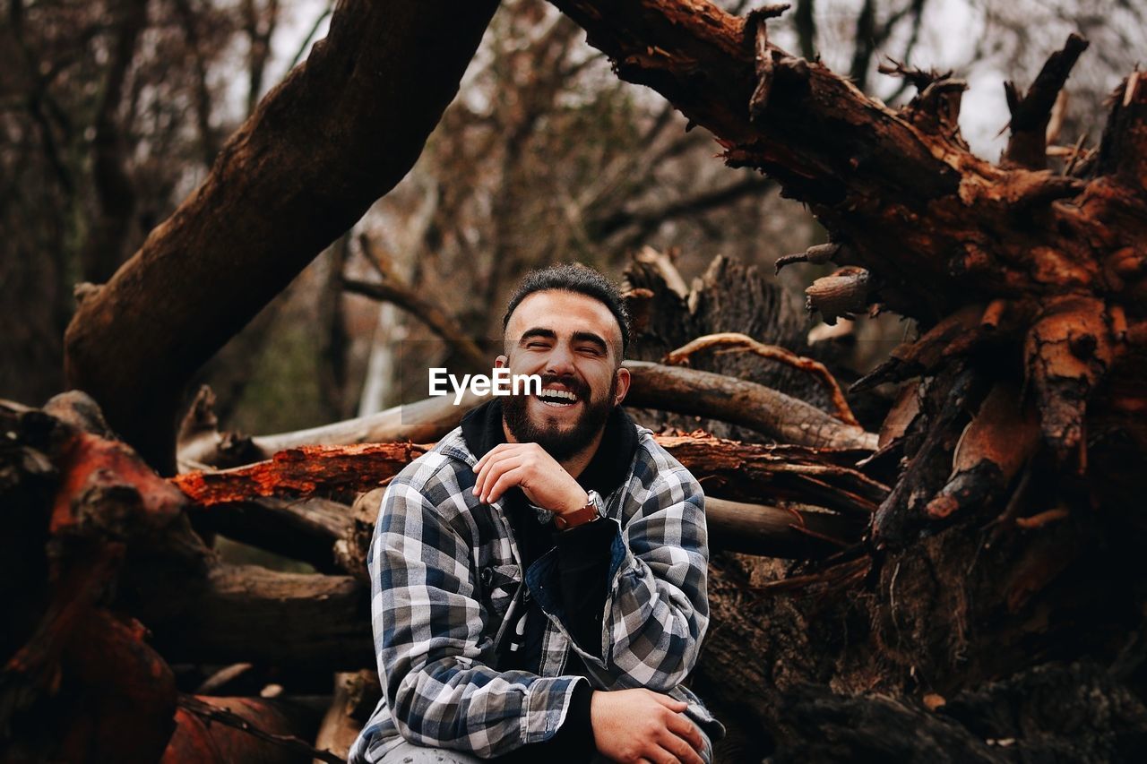 Cheerful man sitting on fallen trees