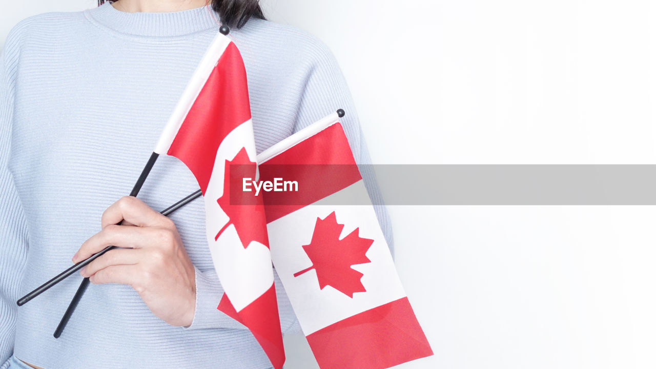 Portrait of woman holding canadian flag against white background