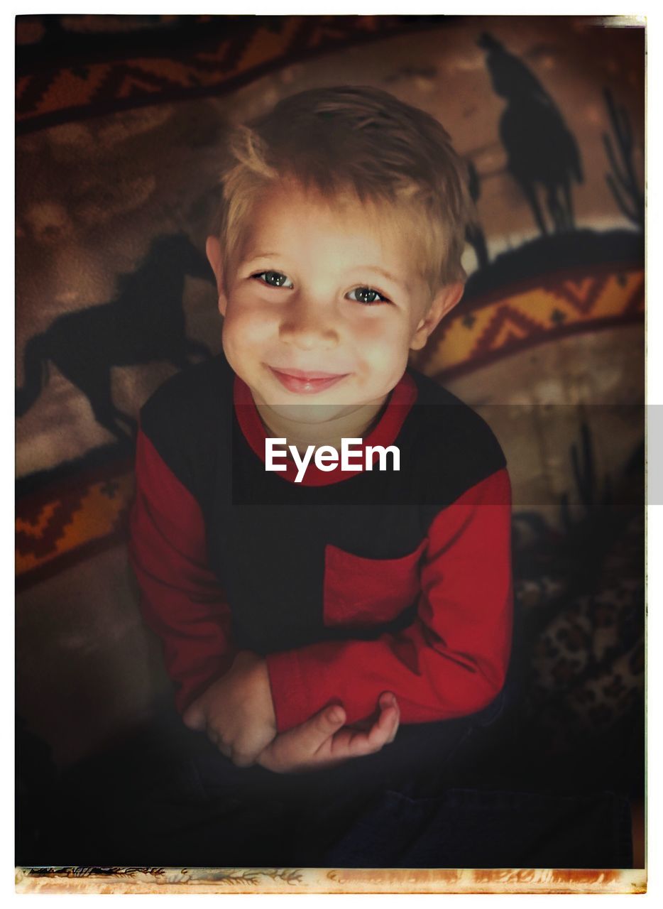 High angle portrait of cute smiling boy sitting at home