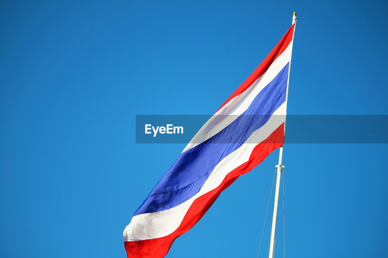 Low angle view of flags flag against clear blue sky