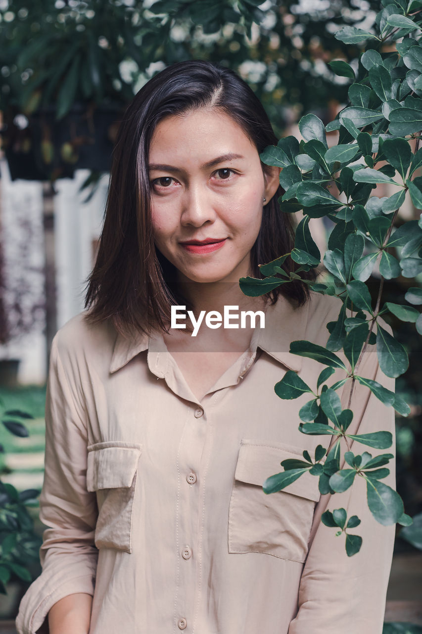 Portrait of beautiful woman standing against plants