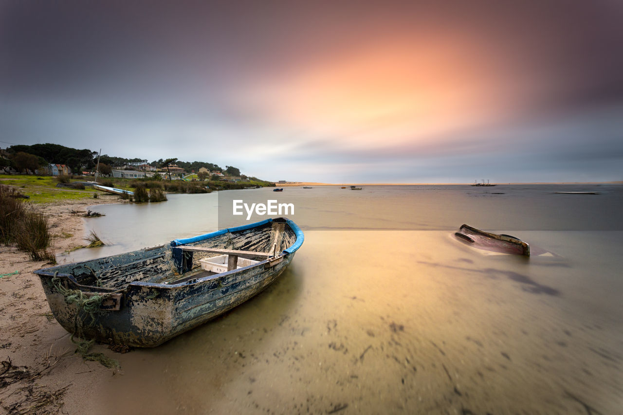 Boat moored on sea against sky during sunset