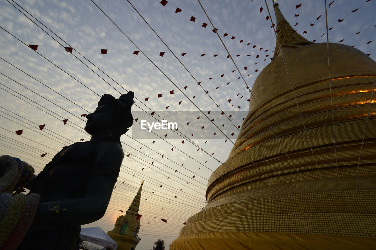 Buddha statue at temple against sky during sunset