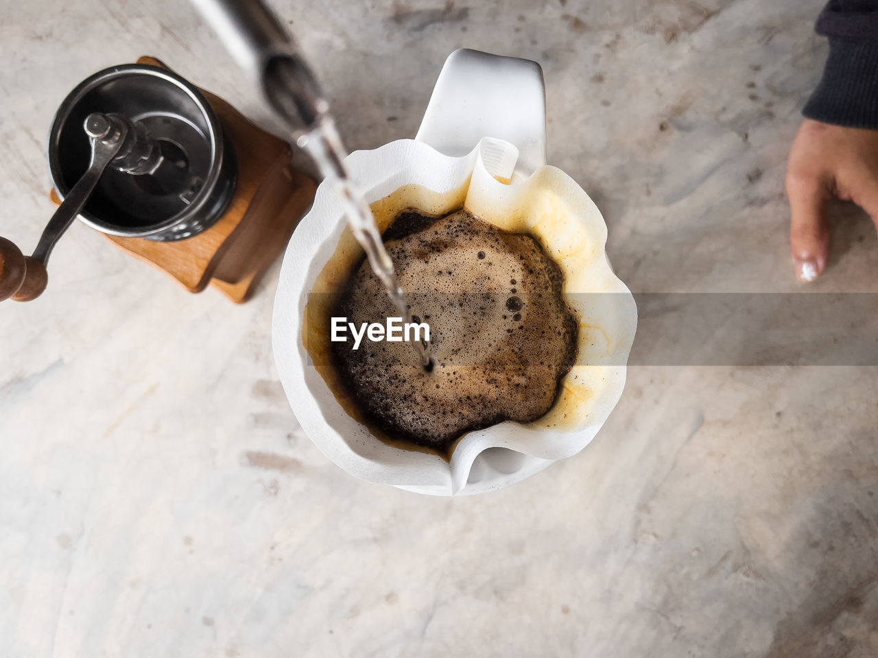 HIGH ANGLE VIEW OF HAND HOLDING COFFEE CUP