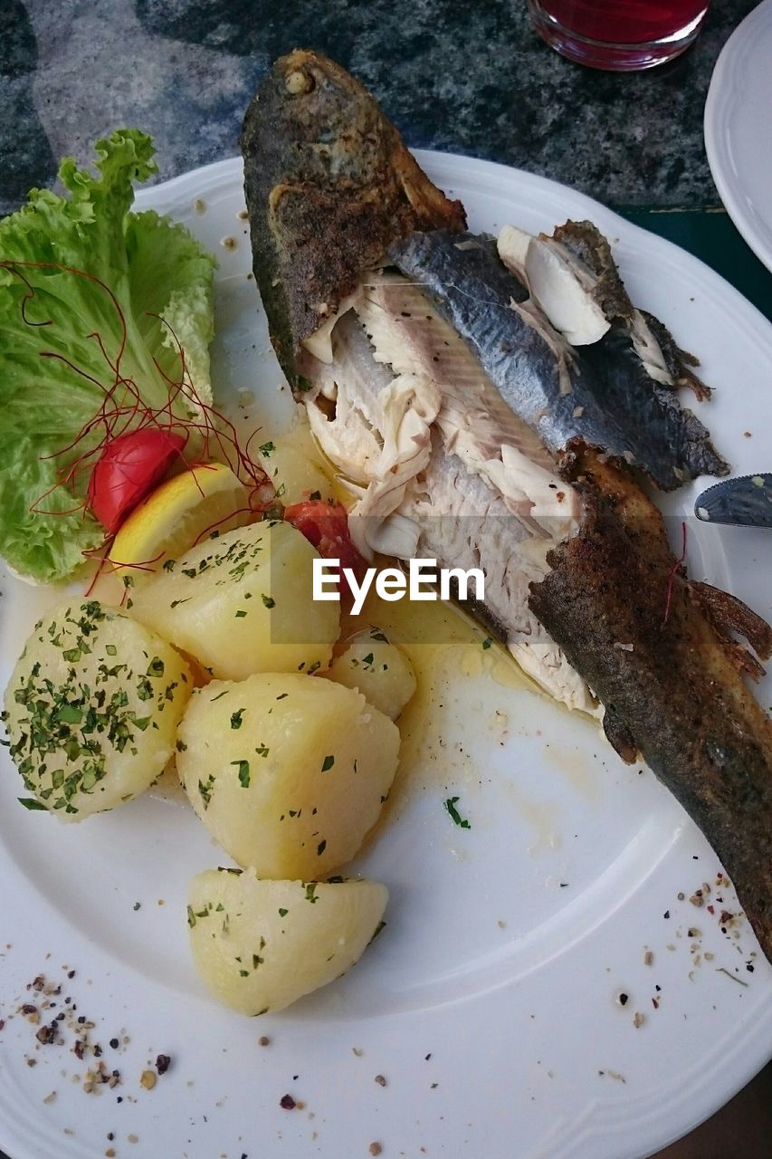 High angle view of fish served with prepared potato and lemon slice in plate