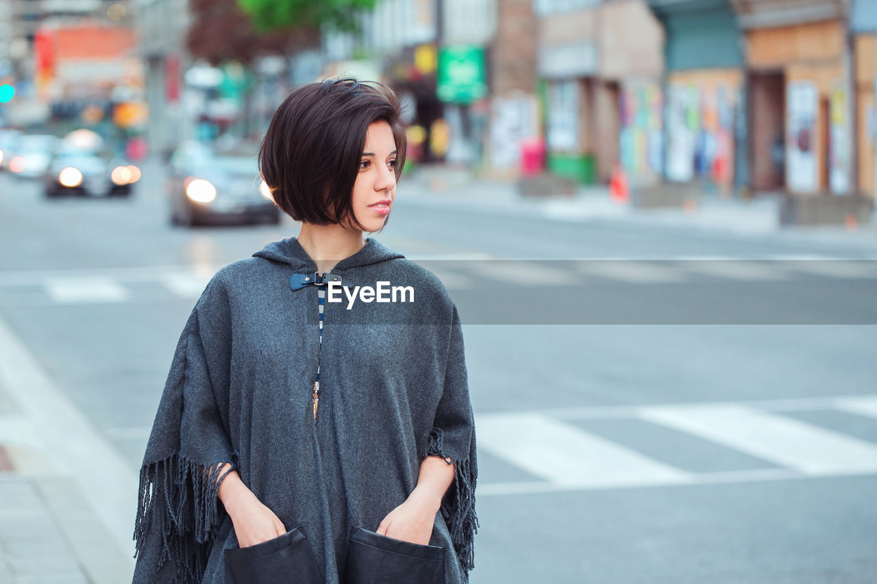 Young woman standing on road in city