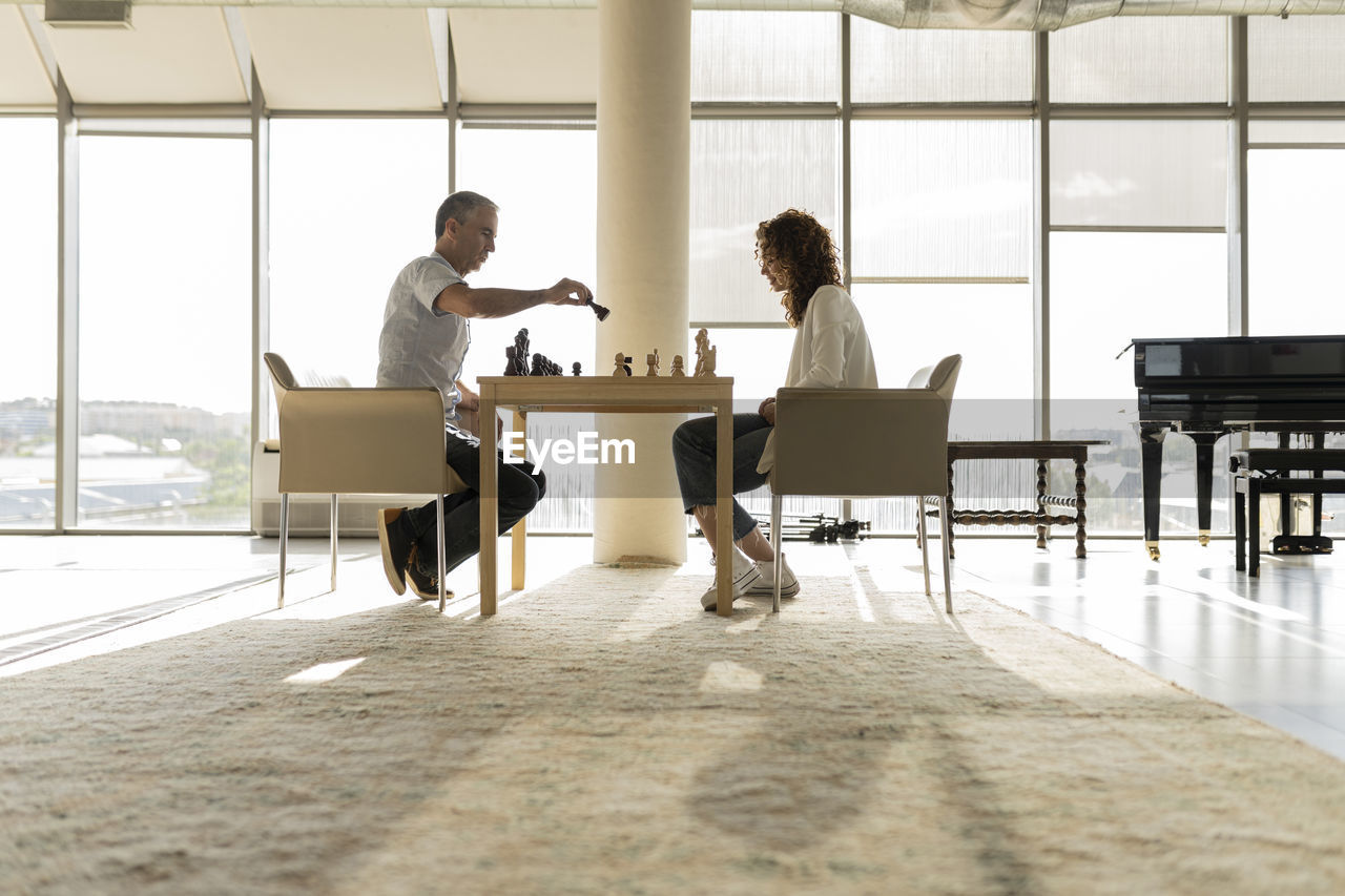 Mature businesswoman playing chess with young colleague in office