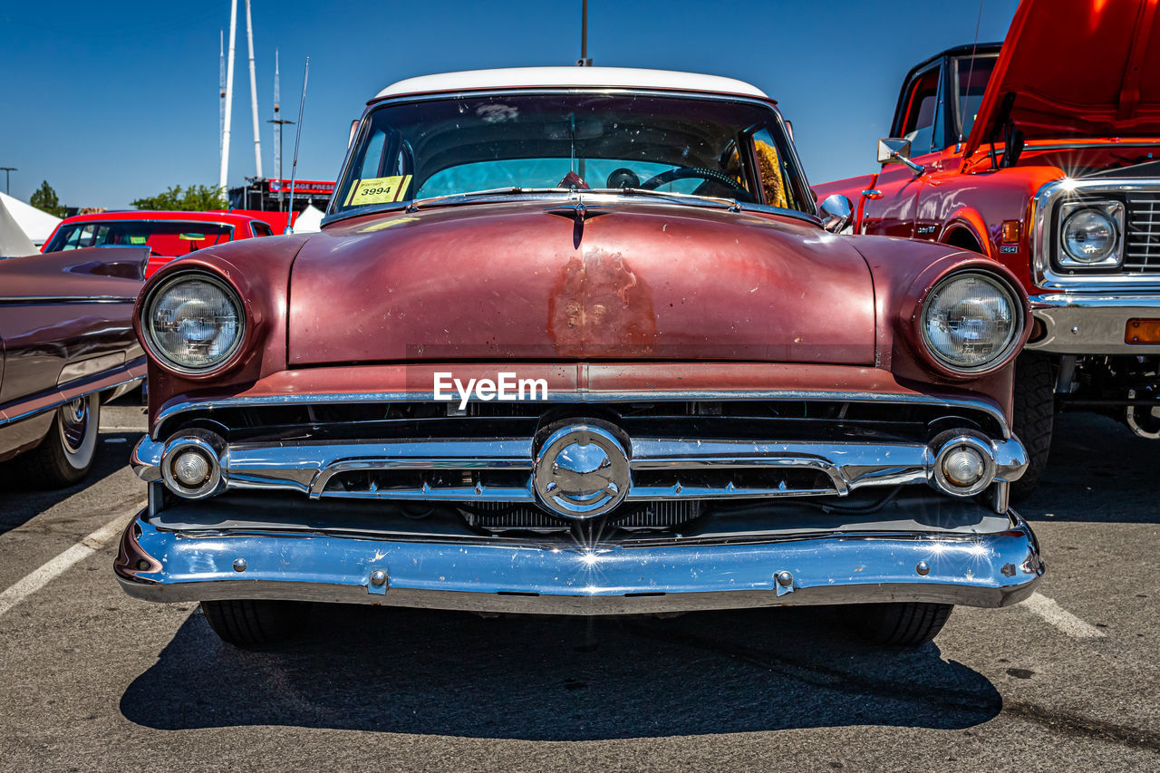 car, vehicle, mode of transportation, land vehicle, transportation, motor vehicle, vintage car, retro styled, antique car, blue, automotive exterior, headlight, collector's car, red, front view, metal, auto show, hot rod, luxury vehicle, architecture, the past, history, automobile, city, grid, no people, sky