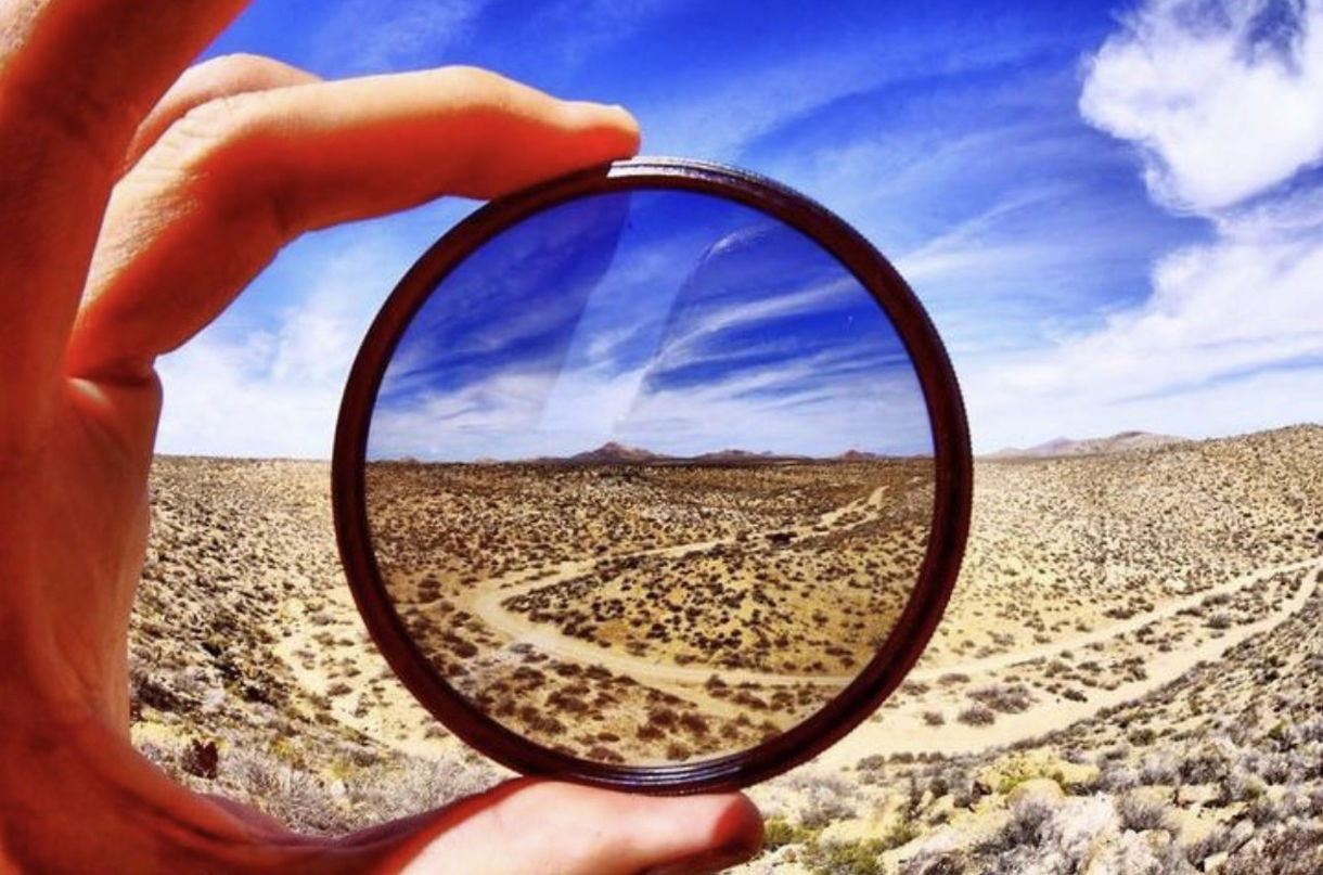 sky, hand, one person, nature, cloud, mirror, circle, land, geometric shape, shape, holding, day, landscape, sunlight, leisure activity, adult, outdoors, environment, close-up, scenics - nature, lifestyles, magnifying glass, beach, looking through an object