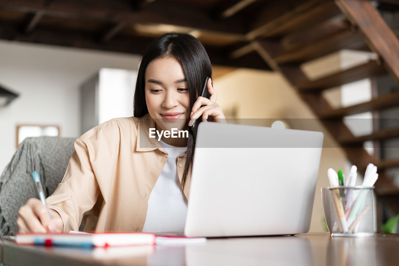 young woman using laptop while sitting on table