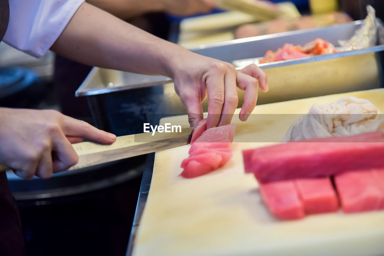 Midsection of chef cutting meat in commercial kitchen