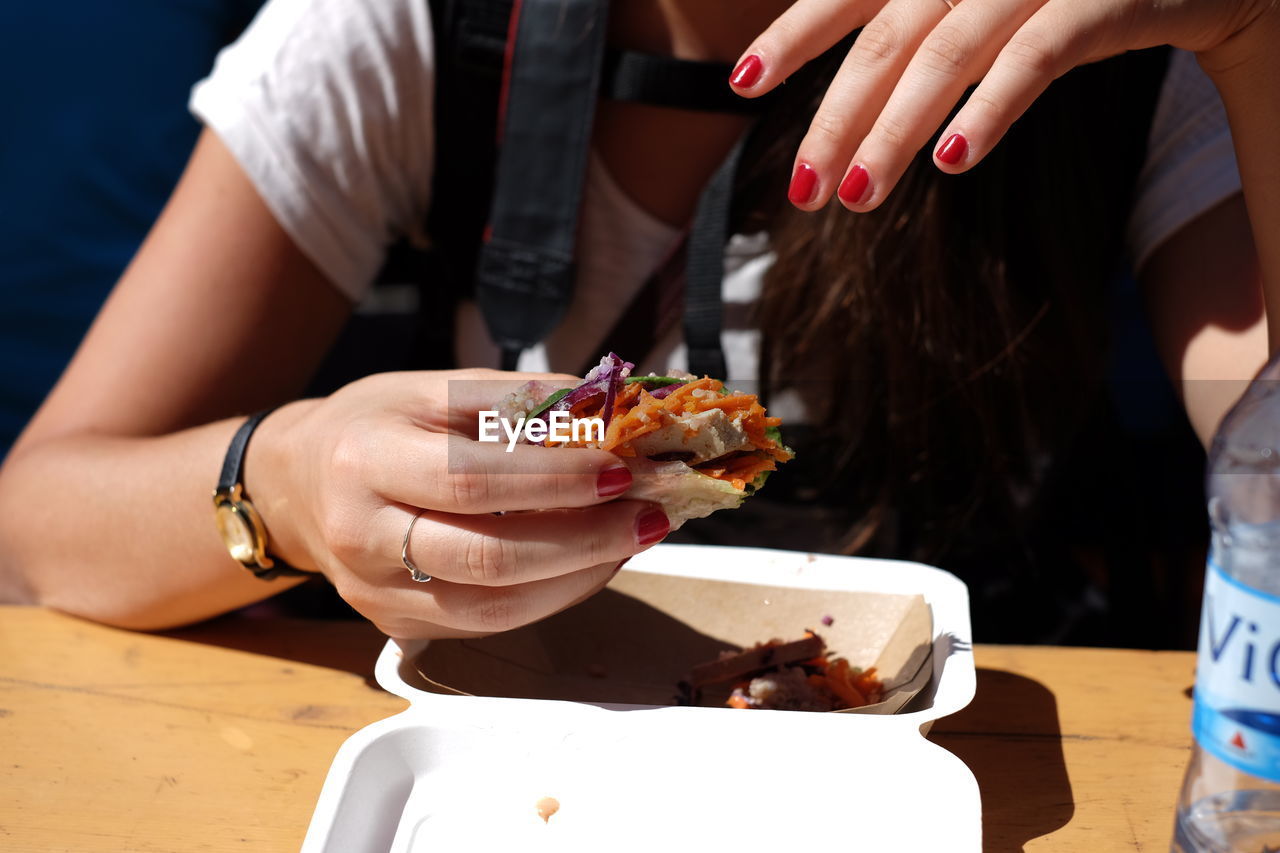 Cropped image of woman holding chicken wrap sandwich