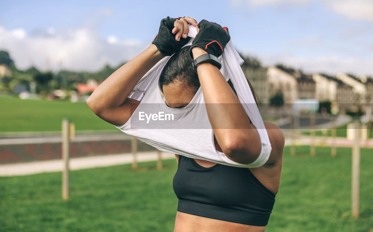 Sportswoman taking off t-shirt at park