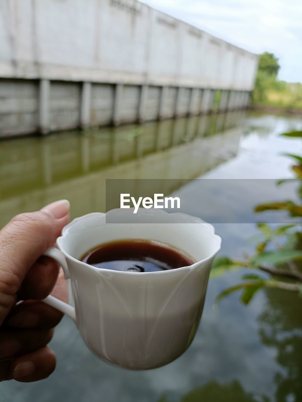 hand, food and drink, drink, one person, holding, cup, refreshment, water, focus on foreground, mug, day, close-up, lifestyles, food, adult, nature, leisure activity, architecture, hot drink, finger, outdoors, coffee, sky, tea