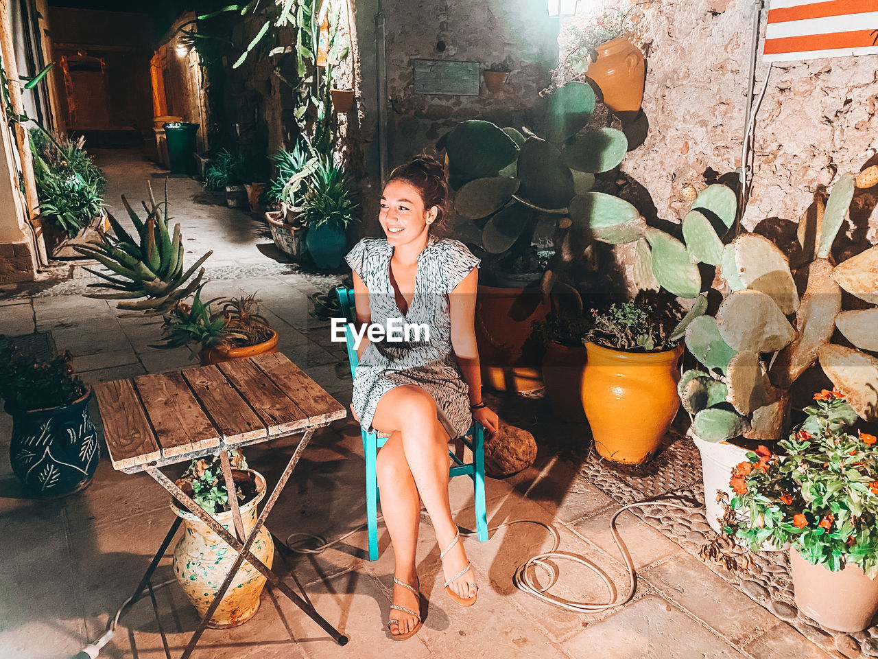 Portrait of young woman sitting on potted plant