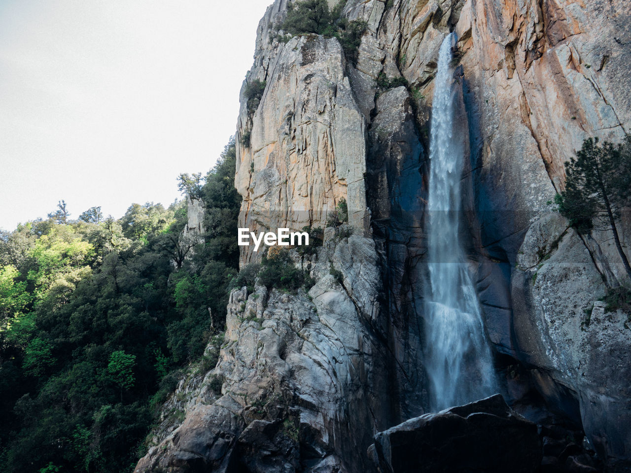 LOW ANGLE VIEW OF WATERFALL ON MOUNTAIN AGAINST SKY