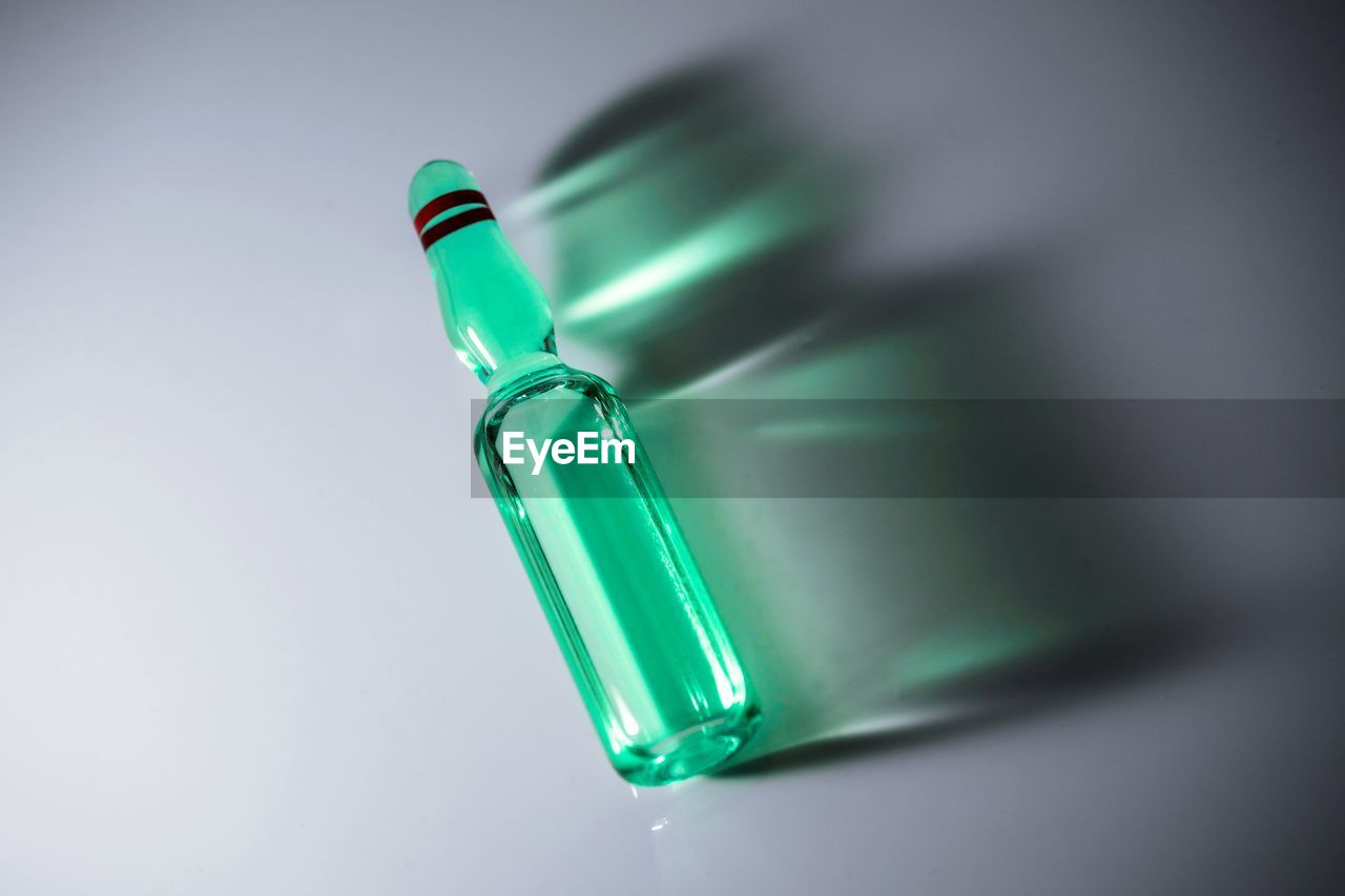 HIGH ANGLE VIEW OF GREEN BOTTLE ON TABLE